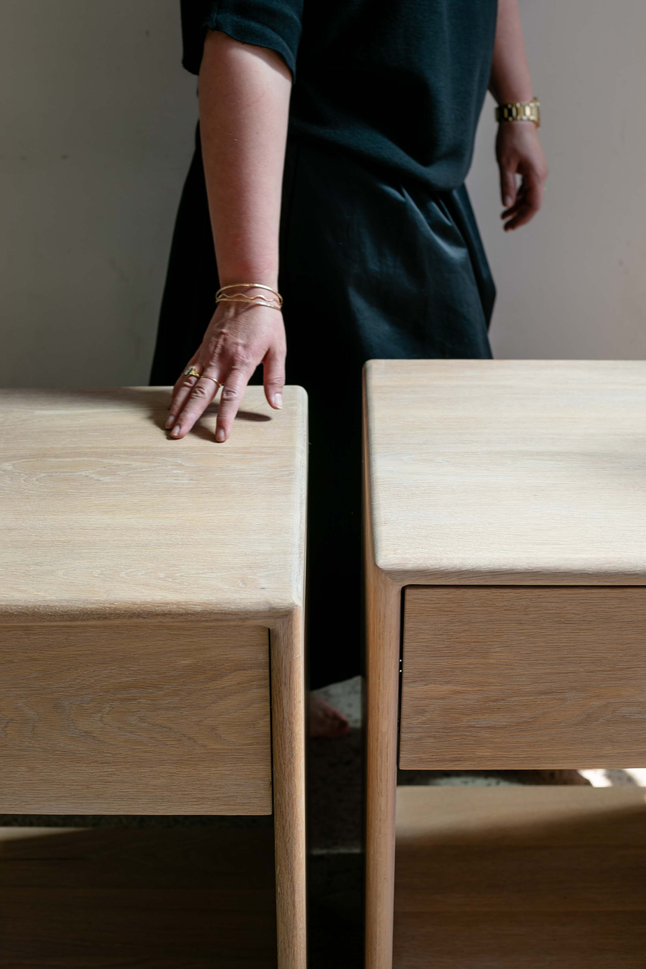 Esterina's hand brushing against the top of smooth white oak night stands by Tavolo Studios. 